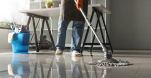 Cleaning in the office Beautiful cleaning lady uses a mop and a vacuum cleaner to clean the floor